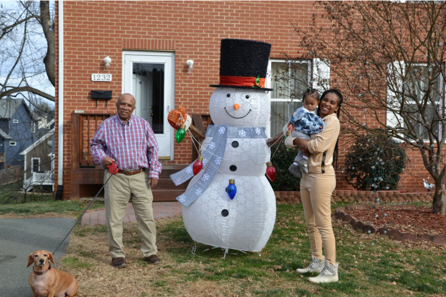 image of family man with dog on leash snow man inflatable and adult daughter hol